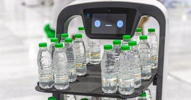 An intelligent robot distributes Zamzam water on visitors to the mosque and pictures
