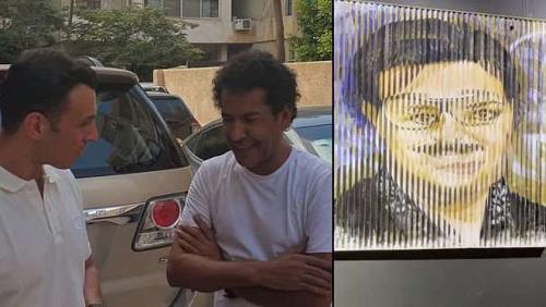 A painter guides a technical plaque for Rami Radwan when moving it shows the image of Dalal and Samir