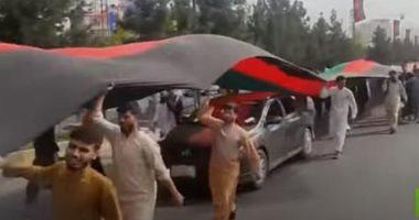 Taliban fighters shoot a march with national flag in Kabul